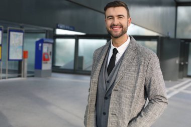 Şehir caddesinde gri takım elbiseli yakışıklı bir gencin portresi.