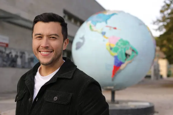 portrait of handsome young man with earth globe on background on city street