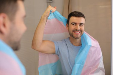 Banyoda aynanın önünde transseksüel bayraklı yakışıklı bir genç portresi.