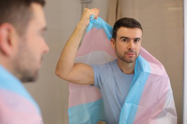 Banyoda aynanın önünde transseksüel bayraklı yakışıklı bir genç portresi.