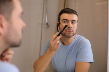 Yakışıklı bir gencin portresi. Banyo da aynanın önünde sakalını ip tıraşıyla tıraş ediyor.