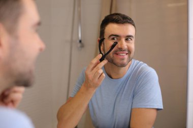 Yakışıklı bir gencin portresi. Banyo da aynanın önünde sakalını ip tıraşıyla tıraş ediyor.