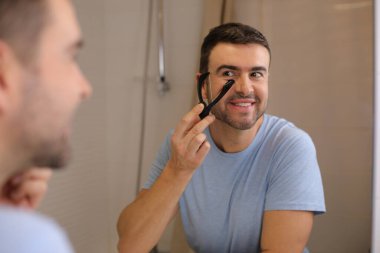 Yakışıklı bir gencin portresi. Banyo da aynanın önünde sakalını ip tıraşıyla tıraş ediyor.