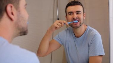Yakışıklı delikanlının banyoda aynanın önünde dişlerini fırçalarkenki görüntüleri.