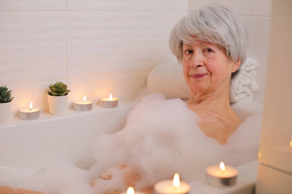 портрет счастливой пожилой женщины, отдыхающей в ванне с мыльными пузырями