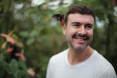 Kafasında güzel bir kelebek olan yakışıklı bir gencin portresi.