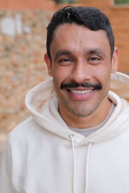 Beyaz kapüşonlu bıyıklı, kameraya gülümseyen yakışıklı İspanyol adamın portresi.