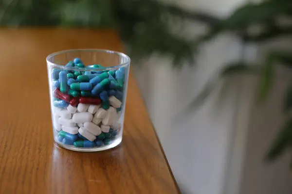 Ahşap Masanın Üzerinde Çeşitli Ilaç Haplarla Dolu Yakın Plan Cam — Stok fotoğraf