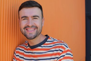 Yakından. Sokakta turuncu gömlekli yakışıklı bir genç.