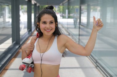 Kulaklıklı güzel bir genç kadının portresi ve sokakta rol patenleriyle müzik dinlemek.