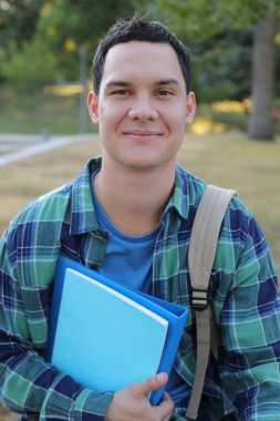 Sırt çantası ve defterleri olan gülümseyen genç bir adamın portresi.