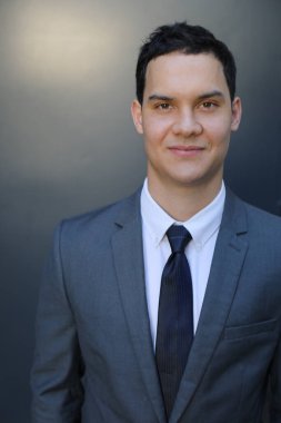 Gri arka planda gülümseyen genç yakışıklı iş adamı