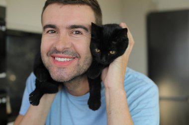 Elinde siyah kedisi olan genç bir adam.