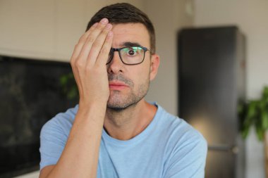 Yüzünde ve gözlüklerinde eli olan yakışıklı adam. 