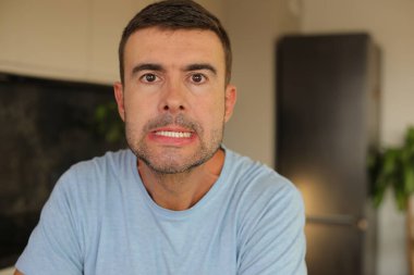 Genç beyaz adam yüz hareketi yapıyor.