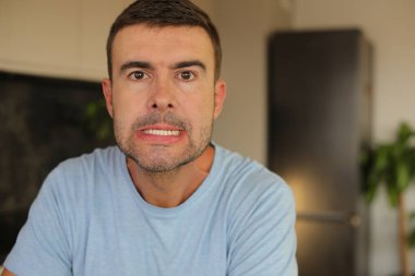 Genç beyaz adam yüz hareketi yapıyor.