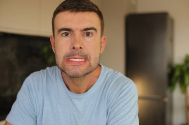 Genç beyaz adam yüz hareketi yapıyor.