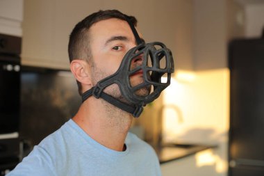 Genç adam evde ağızlık takıyor.