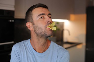 Dudaklarının arasında patates cipsi olan ördek gibi davranan adam.