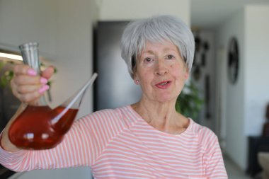 Senior woman drinking with traditional Spanish utensil called 