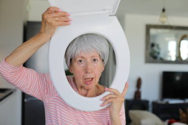 Kıdemli komedyen yüzünün etrafında tuvalet parçası tutuyor.