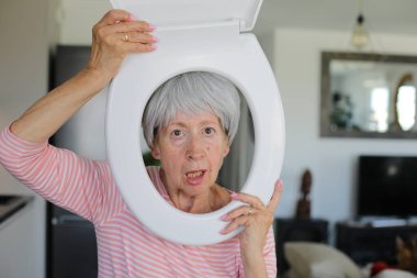 Kıdemli komedyen yüzünün etrafında tuvalet parçası tutuyor.