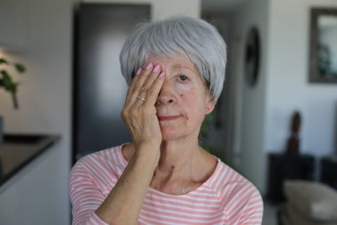 Kıdemli kadın sadece bir gözünü kapatarak görüşünü test ediyor.