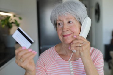 Telefon görüşmesi sırasında kredi kartı tutan şüpheli görünen son sınıf öğrencisi bir kadın.