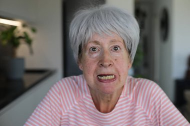 Kıdemli kadın alt dişlerini gösteriyor.