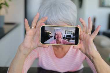 Yaşlı kadın evde selfie çekiyor.