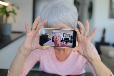 Yaşlı kadın evde selfie çekiyor.