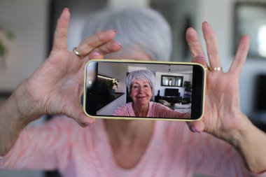Yaşlı kadın evde selfie çekiyor.