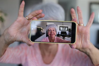 Yaşlı kadın evde selfie çekiyor.