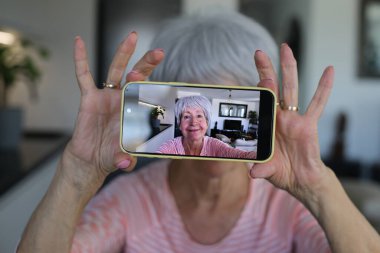 Yaşlı kadın evde selfie çekiyor.