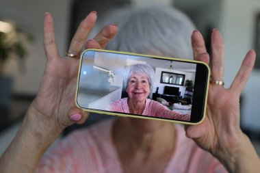Yaşlı kadın evde selfie çekiyor.