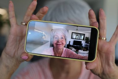 Yaşlı kadın evde selfie çekiyor.