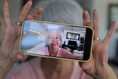 Yaşlı kadın evde selfie çekiyor.