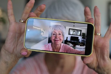 Yaşlı kadın evde selfie çekiyor.