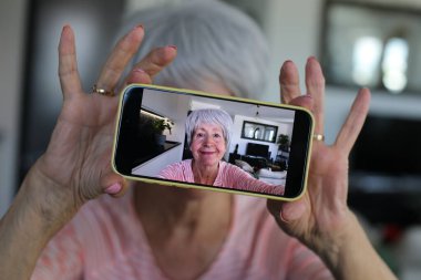 Yaşlı kadın evde selfie çekiyor.