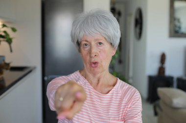 Kıdemli kadın kamerayı parmağıyla işaret ediyor. 