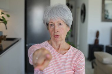 Kıdemli kadın kamerayı parmağıyla işaret ediyor. 