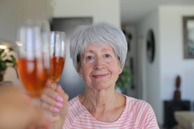 Şampanya kadehli yaşlı kadın.