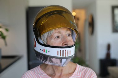 Arka planda koruyucu kask takan yaşlı kadın, yakın plan.