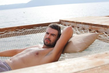 Yakışıklı adam askıya alınmış ağda yatıyor.