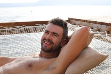 Yakışıklı adam askıya alınmış ağda yatıyor.