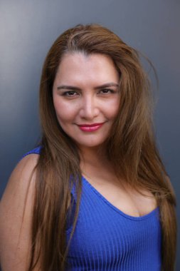 Gri arka planda poz veren çekici bir kadın.