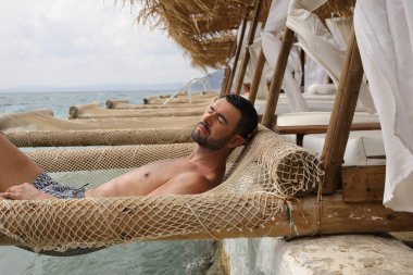 Yakışıklı adam askıya alınmış ağda yatıyor. 