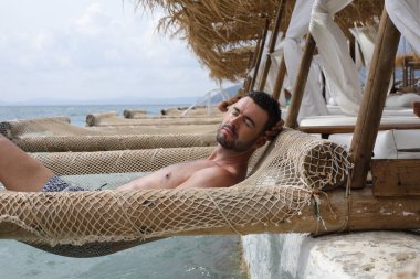 Yakışıklı adam askıya alınmış ağda yatıyor. 