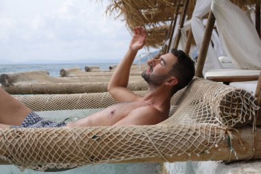 Yakışıklı adam askıya alınmış ağda yatıyor. 