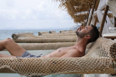 Yakışıklı adam askıya alınmış ağda yatıyor. 